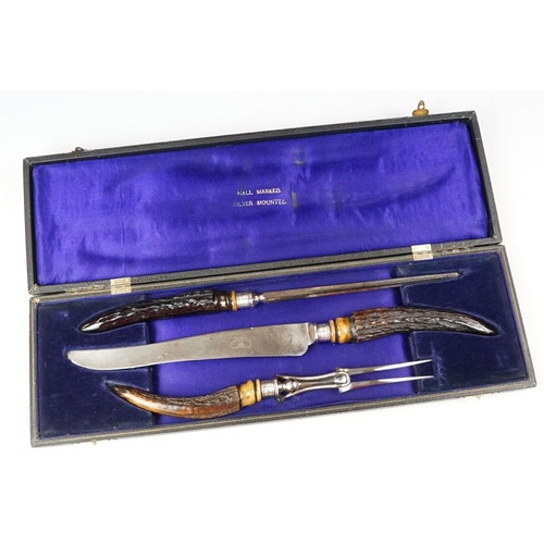 253 - A cased carving set with antler handles and sterling silver mounts.