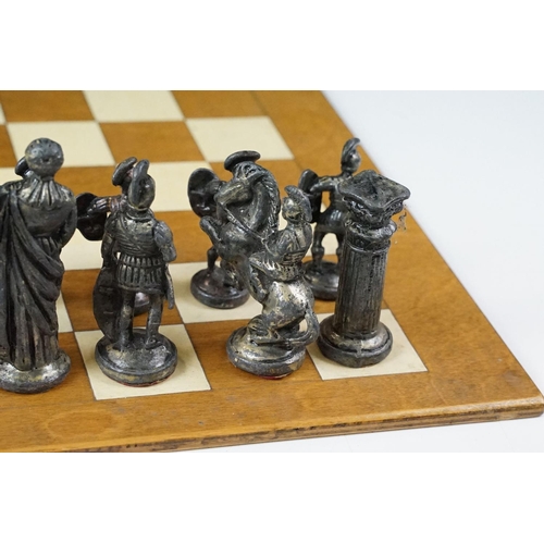 341 - A set of cast metal chessmen in the form of Romans together with a wooden chessboard.