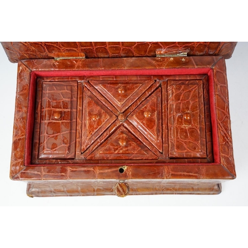393 - An antique Alligator skin jewellery box with fitted segmented interior and complete with key.