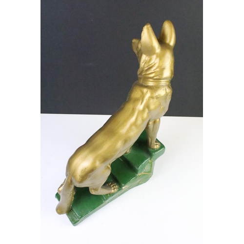 113 - Large chalk painted model of an Alsatian, in gold, climbing green steps, approx 44cm tall