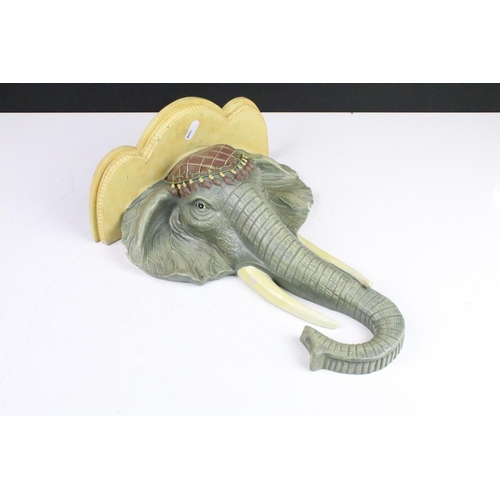 182 - Cast resign wall sconce shelf in the form of an elephant together with two carved wood elephant wall... 