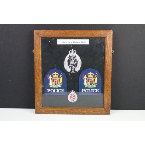 187 - A framed group of Royal New Zealand Police badges together with two police signs.