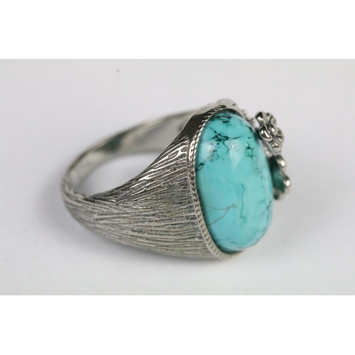 217 - Silver and turquoise ring being set with an oval cabochon to centre with floral detailing and textur... 