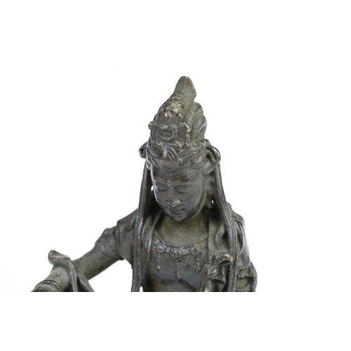 260 - Cast bronze figurine in the form of Guanyin seated on a rock. Measures 11.5cm tall.