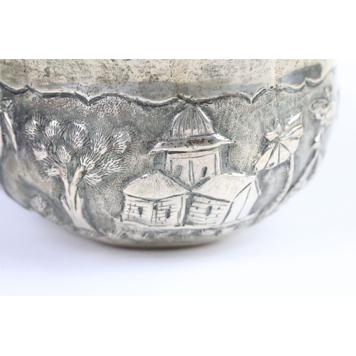 266 - Indian white metal Lucknow bowl having a repousse village scene to the sides with fanned rim. Measur... 