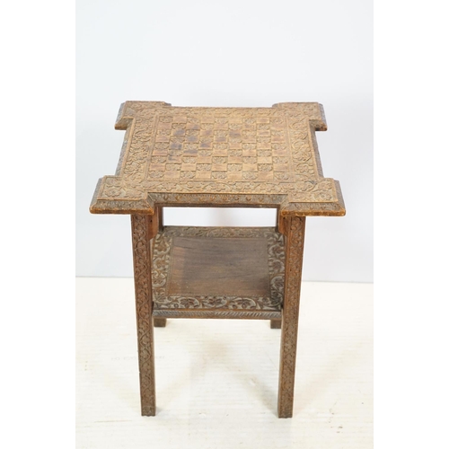 661 - Eastern style two tier occasional table, the florally carved top with 9 x 9 game board, 53cm high x ... 