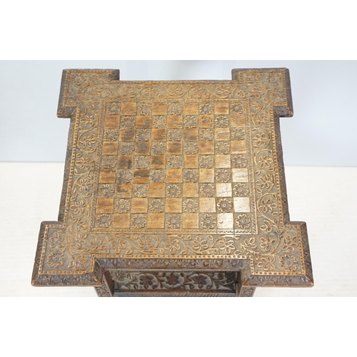 661 - Eastern style two tier occasional table, the florally carved top with 9 x 9 game board, 53cm high x ... 