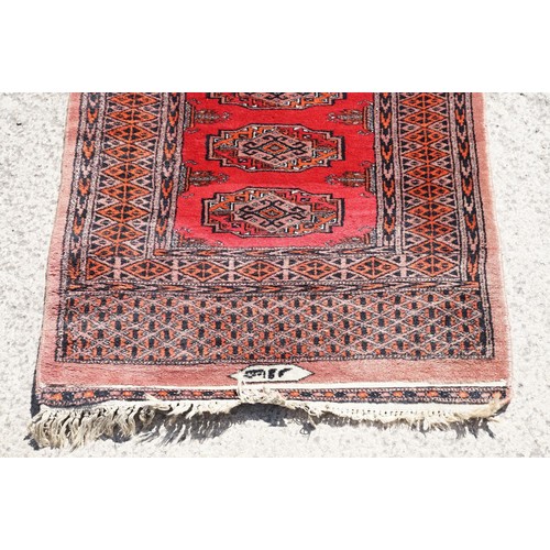 696 - Middle Eastern rug having a red ground with fourteen medallions to centre with geometric borders. Me... 