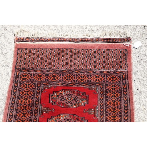 696 - Middle Eastern rug having a red ground with fourteen medallions to centre with geometric borders. Me... 