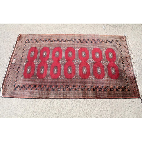 691 - Middle Eastern carpet rug having a red ground with medallions to central panel and geometric borders... 