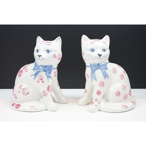 19 - Pair of Rye pottery models of seated cats, white with pink spots wearing blue bows, 20cm high