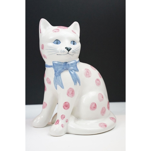 19 - Pair of Rye pottery models of seated cats, white with pink spots wearing blue bows, 20cm high