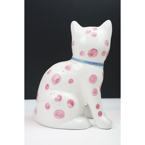 19 - Pair of Rye pottery models of seated cats, white with pink spots wearing blue bows, 20cm high