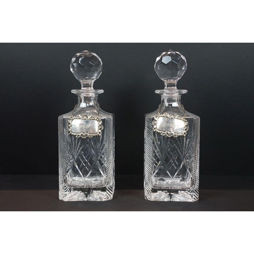 6 - Two crystal glass decanters of square form with stoppers, with two silver hallmarked decanter labels... 