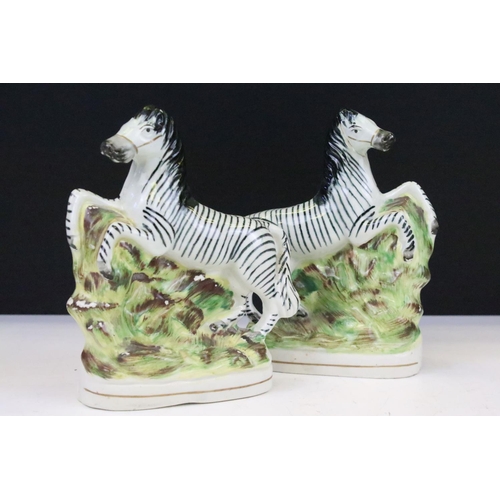 16 - Pair of Staffordshire rearing zebra porcelain figures on a naturalistic ground, 16cm high, together ... 