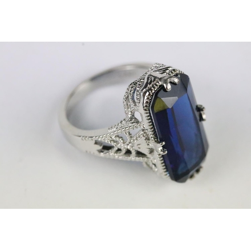 164 - A ladies 925 sterling silver dress ring with central blue stone and decorative pierced shoulders, ma... 