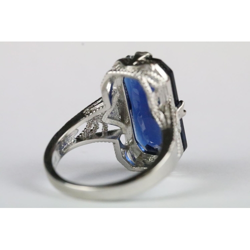 164 - A ladies 925 sterling silver dress ring with central blue stone and decorative pierced shoulders, ma... 