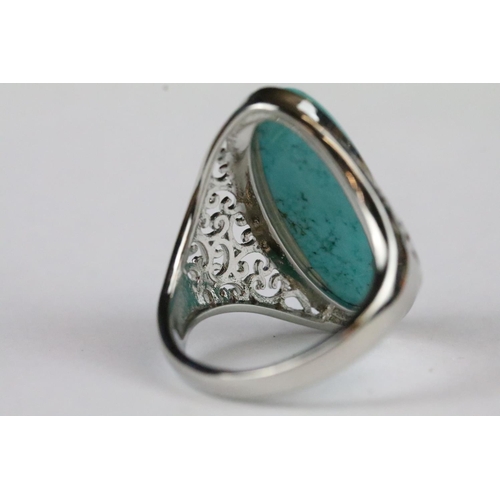 176 - A ladies 925 sterling silver ring with central turquoise cabochon, pierced decoration to shoulders, ... 