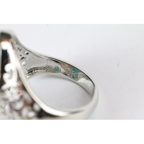 176 - A ladies 925 sterling silver ring with central turquoise cabochon, pierced decoration to shoulders, ... 