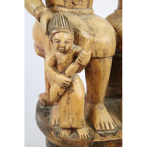 262 - Large African carved hardwood figure of two women and two children sitting on a face mask, 113cm hig... 