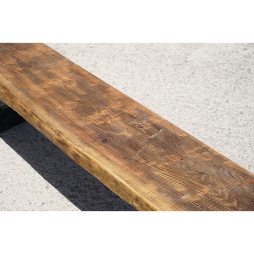 289 - A large contemporary pine single plank garden bench, mounted to two semi circular wrought iron legs,... 