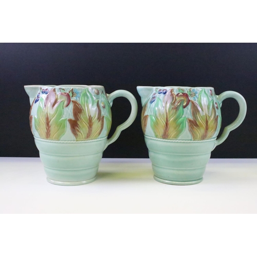 34 - Clarice Cliff for Newport Pottery - Pair of leaf & berry pattern molded jugs on a celadon type groun... 