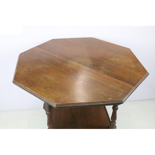 344 - Early 20th C table of hexagonal form on four turned legs, with lower central shelf, on brass casters... 