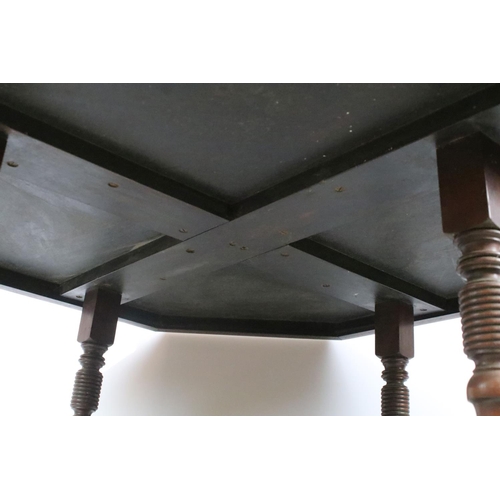 344 - Early 20th C table of hexagonal form on four turned legs, with lower central shelf, on brass casters... 