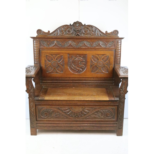 358 - Early 20th century carved oak settle, the pediment carved with lion mask above panelled back and arm... 