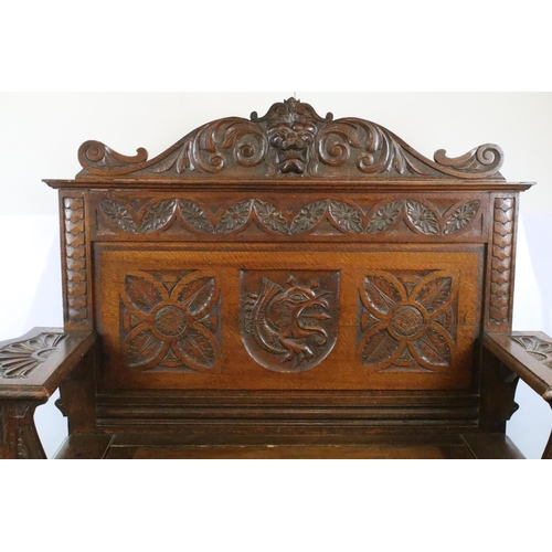 358 - Early 20th century carved oak settle, the pediment carved with lion mask above panelled back and arm... 