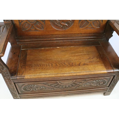 358 - Early 20th century carved oak settle, the pediment carved with lion mask above panelled back and arm... 