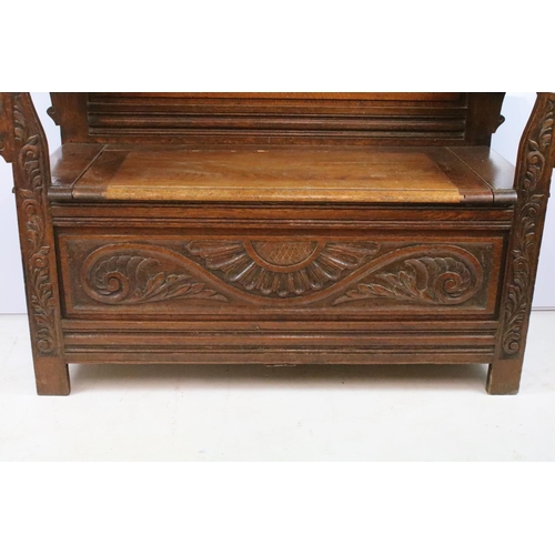 358 - Early 20th century carved oak settle, the pediment carved with lion mask above panelled back and arm... 