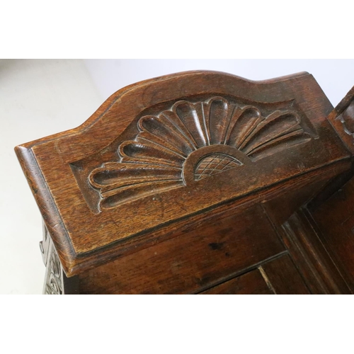 358 - Early 20th century carved oak settle, the pediment carved with lion mask above panelled back and arm... 