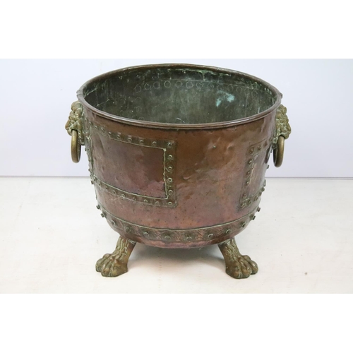 45 - Victorian riveted copper log basket with twin lion mask handles, on four claw feet, 43cm high x 50cm... 