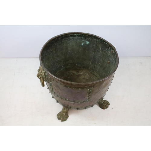 45 - Victorian riveted copper log basket with twin lion mask handles, on four claw feet, 43cm high x 50cm... 