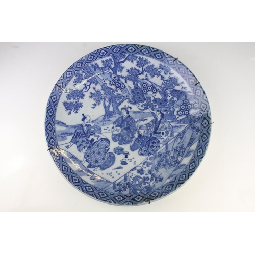 325 - Large Oriental blue & white charger depicting figures seated by a blossoming tree, approx 40cm diame... 