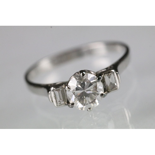 42 - Platinum and diamond three stone ring being set with a round brilliant cut diamond to centre flanked... 