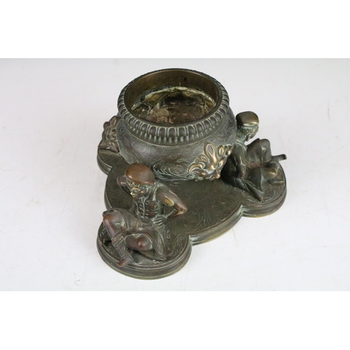 126 - Bronze writing desk ink well holder in the form of a circular lidded receptacle supported by three w... 