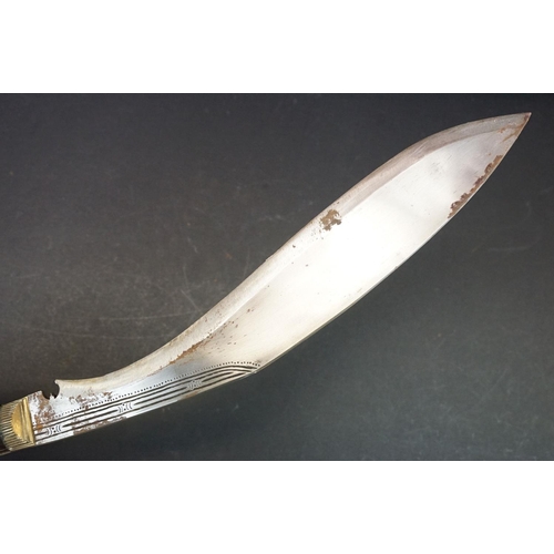 105 - A Kukri knife, dot engraved hollow ground steel blade, horn handle with brass fixings, leather cover... 