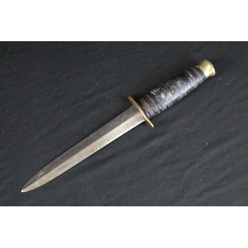 124 - A vintage mid 20th century hunting / fighting knife, double edged blade, brass hilt, leather handle ... 