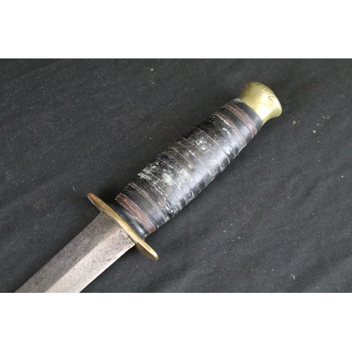 124 - A vintage mid 20th century hunting / fighting knife, double edged blade, brass hilt, leather handle ... 