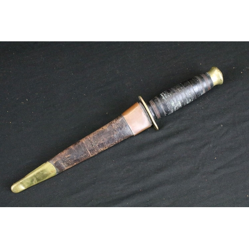 124 - A vintage mid 20th century hunting / fighting knife, double edged blade, brass hilt, leather handle ... 