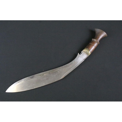 182 - A mid 20th century Kukri knife, steel blade with fullered groove, turned wooden handle, brass flat p... 