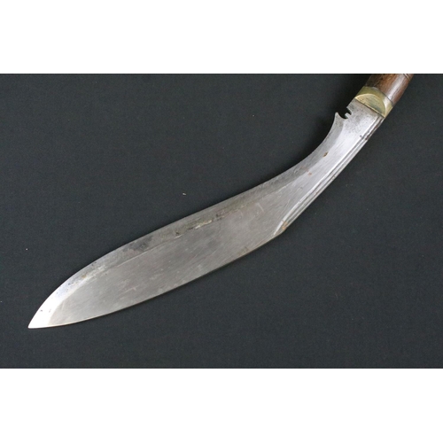 182 - A mid 20th century Kukri knife, steel blade with fullered groove, turned wooden handle, brass flat p... 