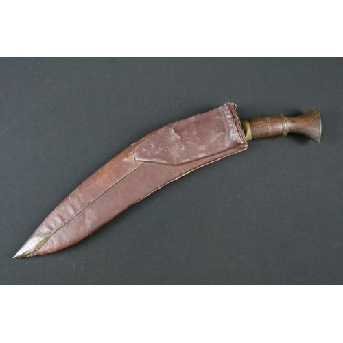 182 - A mid 20th century Kukri knife, steel blade with fullered groove, turned wooden handle, brass flat p... 