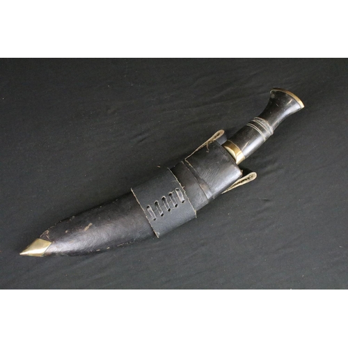 78 - A standard issue (BSI) Kukri knife, horn handle and brass fittings, with black leather covered woode... 