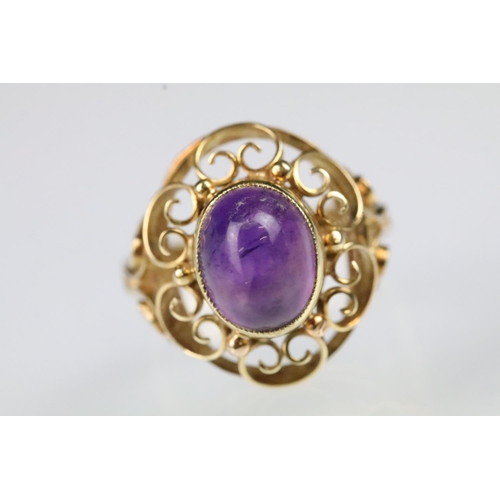 60 - 15ct gold and amethyst ring. The ring being set with an oval amethyst cabochon set within a pierced ... 
