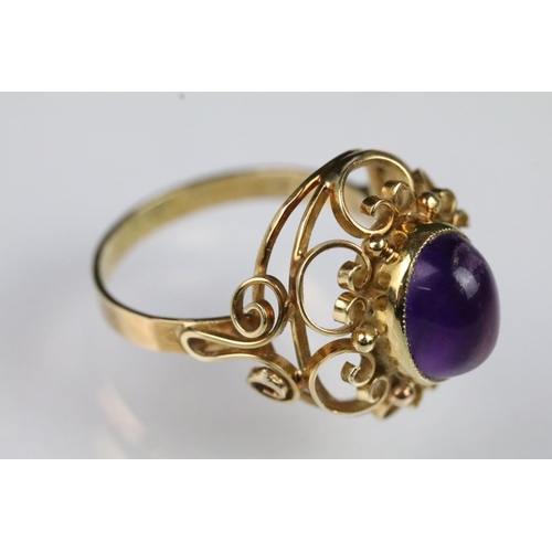 60 - 15ct gold and amethyst ring. The ring being set with an oval amethyst cabochon set within a pierced ... 