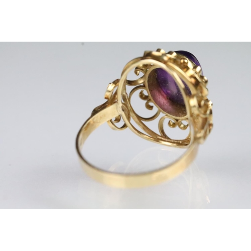 60 - 15ct gold and amethyst ring. The ring being set with an oval amethyst cabochon set within a pierced ... 