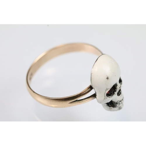13 - 9ct gold and enamel skull ring. The ring being set with  a white enamelled skull to the head set wit... 